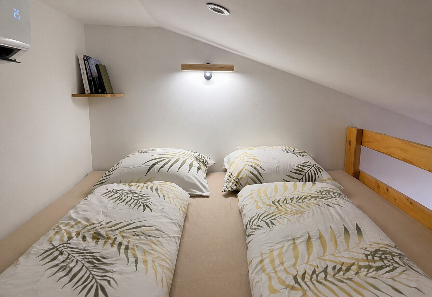 Mezzanine with twin beds under the eaves, reading light and bookshelf